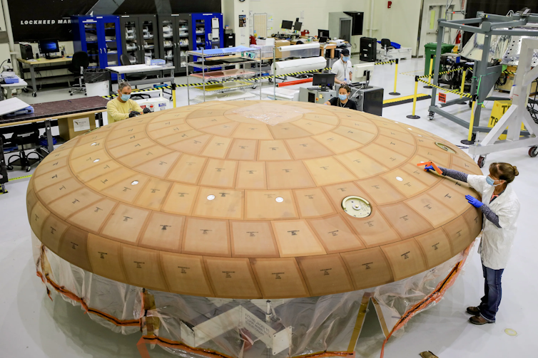 A large round shield covered in small tiles sitting in a laboratory.